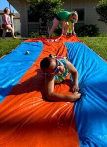 A camper slides down a slip and slide