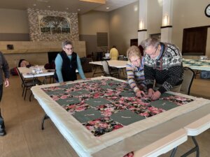 Pastor Mark Kvale of English Lutheran Church ties quilts with the church’s quilting group.