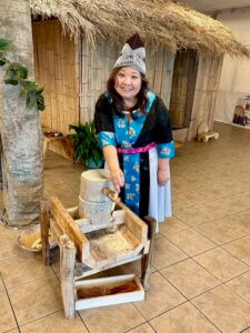 Mai Tia Yang of the Hmong Cultural & Community Center demonstrates how to use a Hmong corn grinder during the Hmong Education Project.